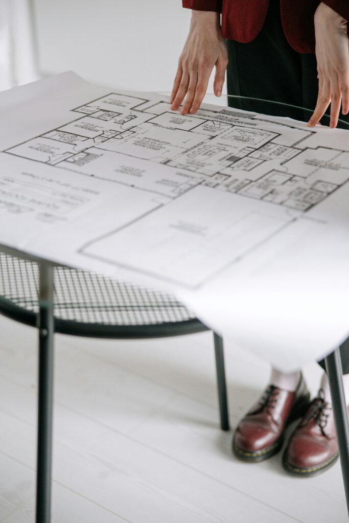 Person examining a detailed architectural floor plan on a table indoors with a focus on design.